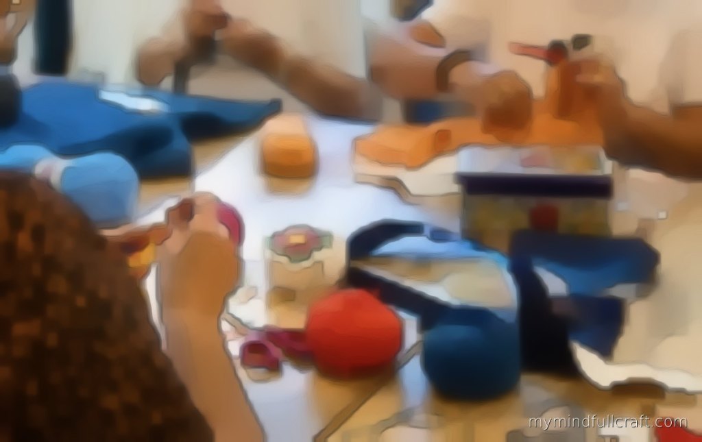 Students crocheting together at a shared table covered in colourful yarn and projects