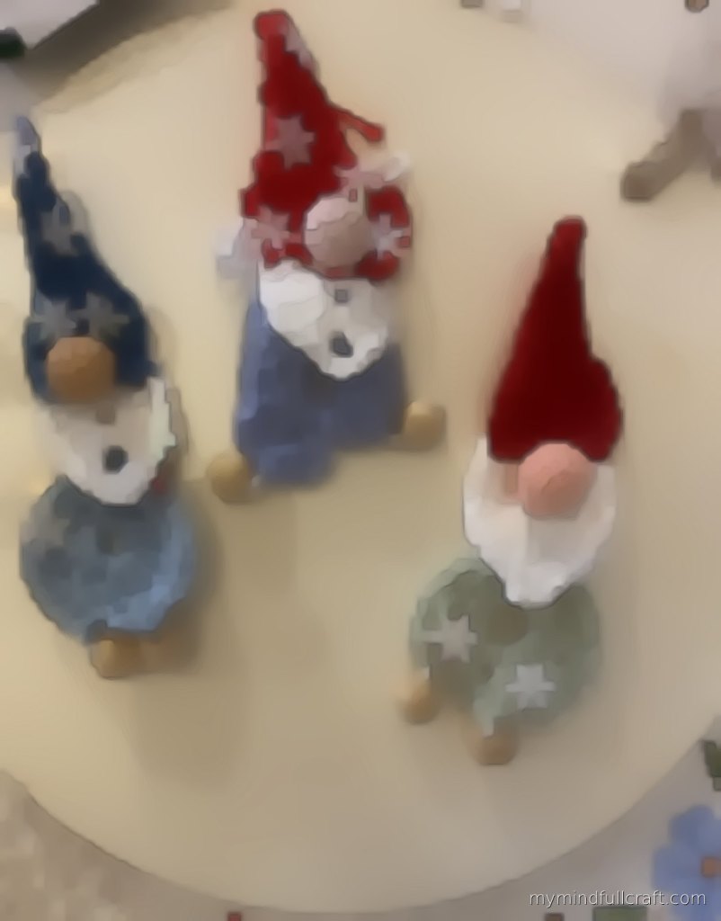 Three small crocheted Christmas gnomes with snowflake sequins and wooden bead feet