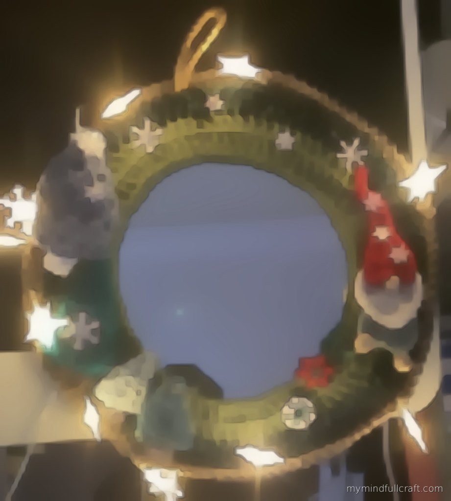 A student's crocheted mirror wreath in greens with a gnome, snowflakes and star fairy lights
